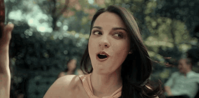 a woman with a surprised look on her face is holding a bottle in her hand
