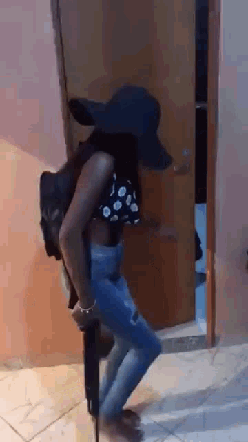 a woman wearing a hat and holding a gun is standing in a doorway .