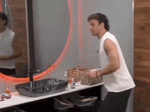 a man in a white tank top is standing in front of a mirror in a bathroom