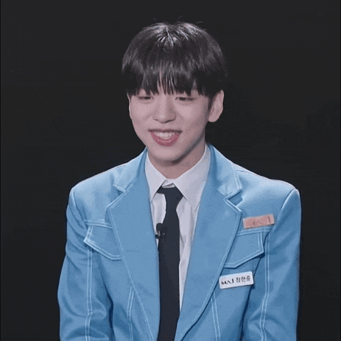 a young man wearing a blue jacket and tie has a name tag that says ' s.n.i. ' on it