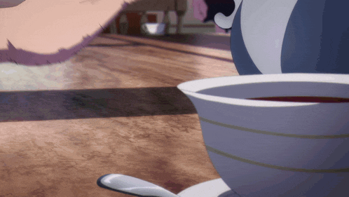 a cup of tea sits on a saucer next to a spoon