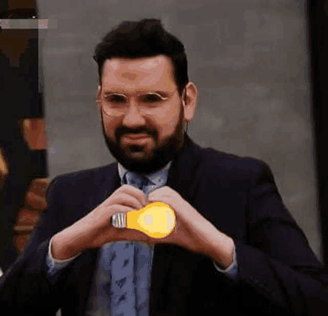 a man in a suit and tie is holding a light bulb between his hands .