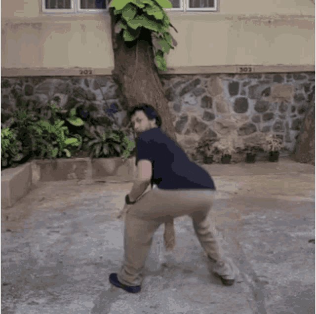 a man is squatting down in front of a stone wall with the number 202 on it