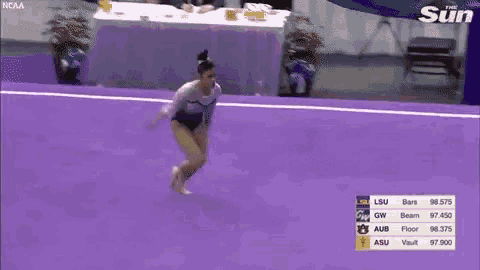 a female gymnast is doing a routine on a purple mat .
