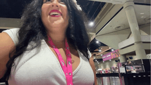 a woman wearing a lanyard that says ' i am a woman ' on it smiles