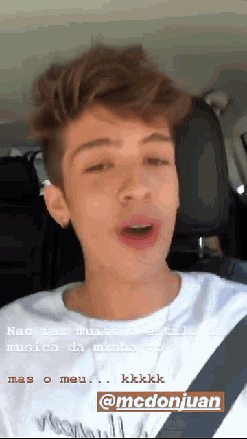 a young man is sitting in a car with the name mcdonjuan on the bottom right