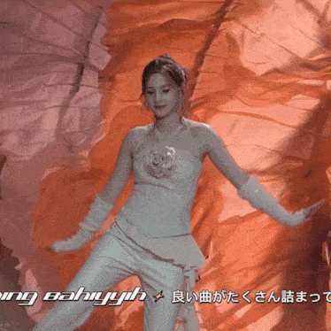 a woman in a white dress is dancing in front of a wall that says ' ing bahyuh ' on it