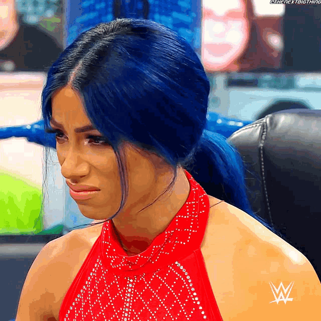 a woman with blue hair is wearing a red dress with a w logo