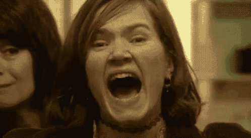a woman is making a funny face with her mouth open in a close up .