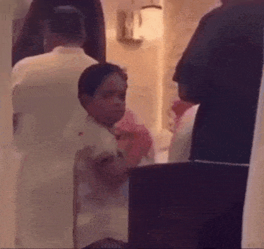 a group of people are standing in a room and a little boy is standing in the middle of the room .