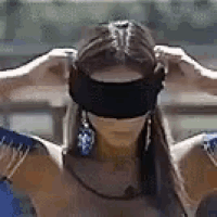 a woman is wearing a blindfold and earrings while standing with her arms outstretched .