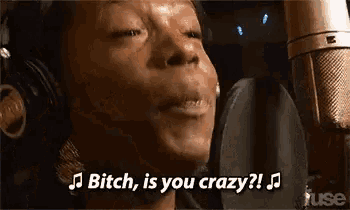 a woman wearing headphones is singing into a microphone and saying `` bitch , is you crazy ? '' .