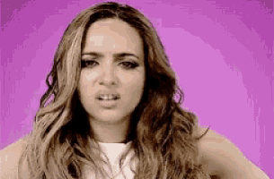 a woman with long wavy hair is making a funny face on a purple background .