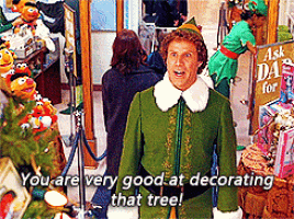 a man in an elf costume is standing in front of a christmas tree and says you are very good at decorating that tree