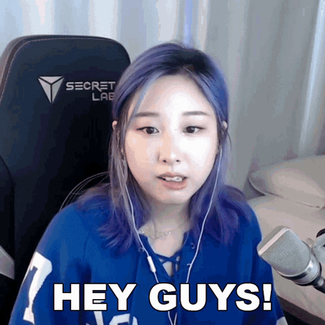 a girl with purple hair is wearing a blue shirt that says hey guys