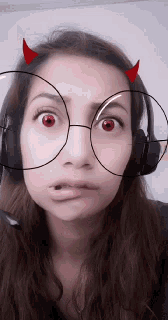 a woman wearing devil horns and headphones makes a face