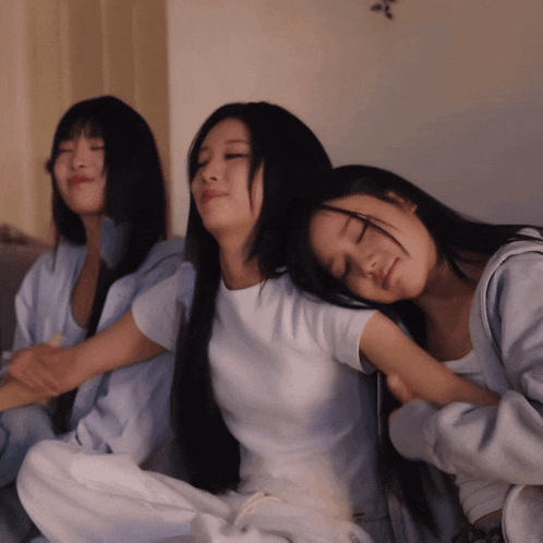 three women are sitting on a couch and one is sleeping
