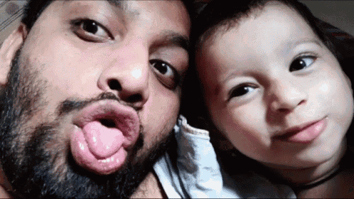 a man with a beard is sticking his tongue out next to a little girl
