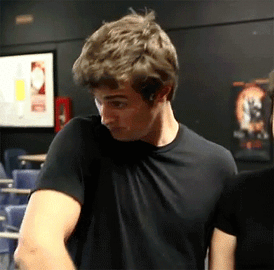 a man in a black shirt is standing in a dark room with a fire extinguisher in the background .