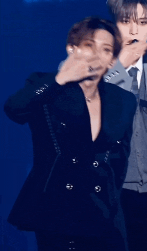 a man covering his mouth with his hand while wearing a black jacket