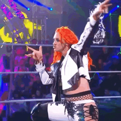 a woman with red hair is kneeling in a wrestling ring with her arms outstretched