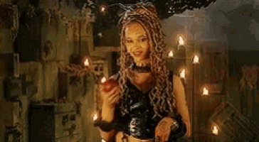 a woman with dreadlocks is holding an apple in a dark room with candles .