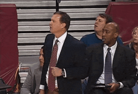 a group of men in suits and ties are sitting in a stadium watching a game
