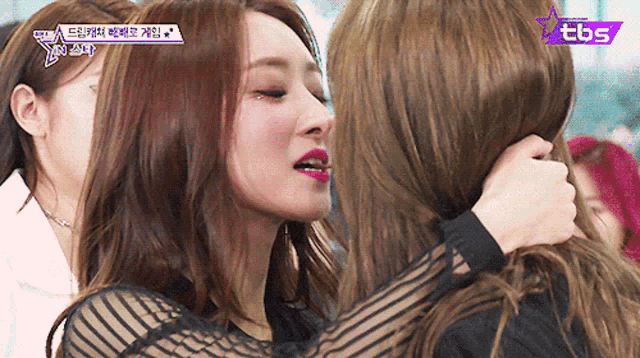 two women are hugging each other with a tbs logo in the corner