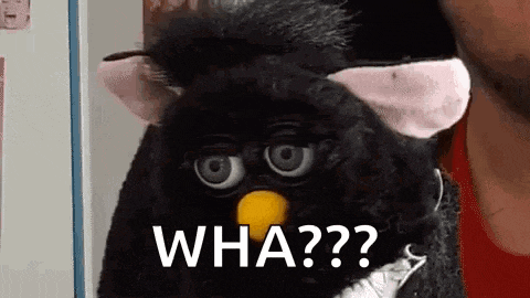 a black furby with a yellow beak is sitting next to a man in a red shirt .