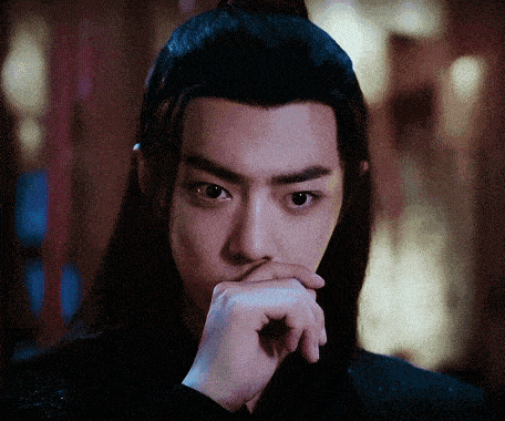a man with long hair is covering his mouth with his hand