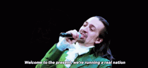 a man is holding a microphone and saying welcome to the present , we 're running a real nation