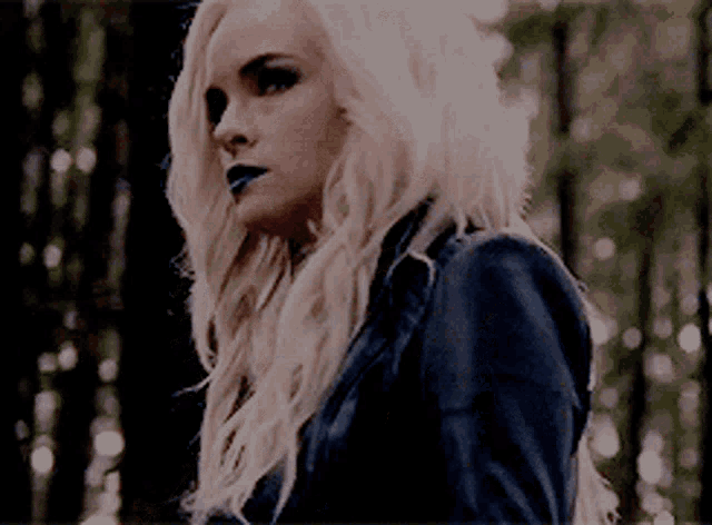 a woman with blonde hair and black lipstick is wearing a black jacket .