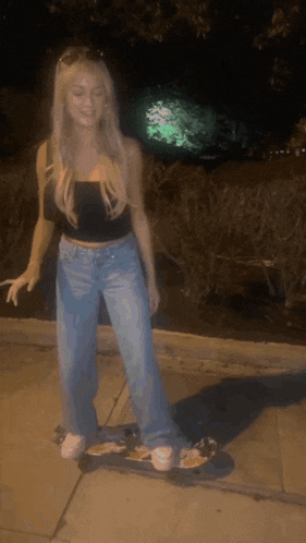a woman is standing on a skateboard at night .