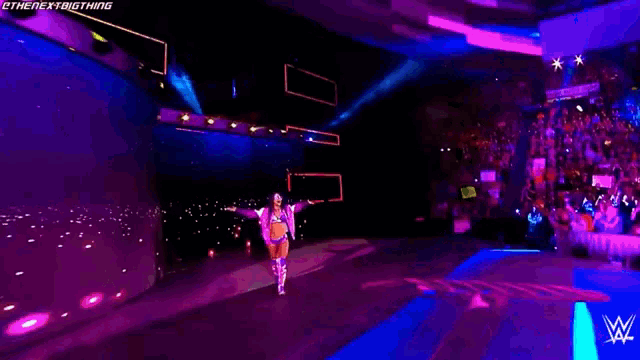 a woman in a wrestling outfit is walking on a stage with a wwe logo on it .