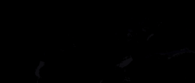a man laying on a bed with another man laying next to him in the dark