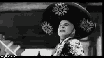 a black and white photo of a man wearing a sombrero and a suit .