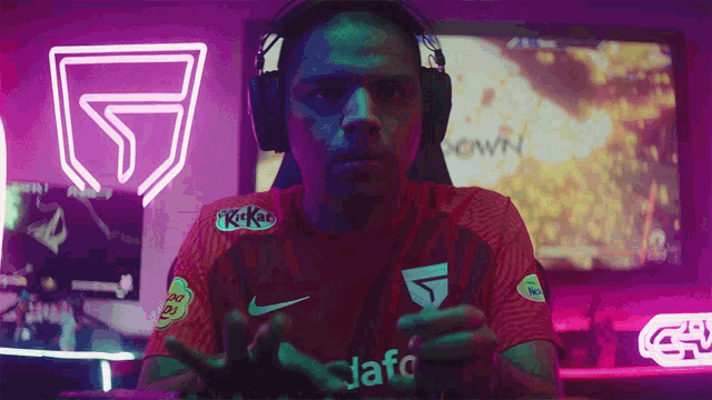 a man wearing headphones and a kitkat shirt is playing a game