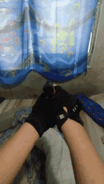 a person wearing a pair of 5.11 gloves laying on a bed