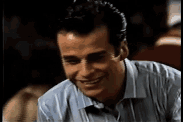 a man in a striped shirt is smiling and looking down .