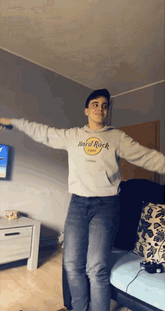 a young man wearing a hard rock cafe sweatshirt is dancing