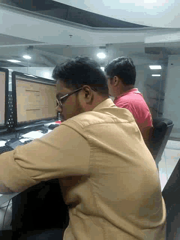 two men are looking at a computer screen and one of them has glasses on