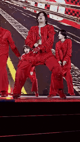 a man in a red jacket and pants is dancing on a stage .