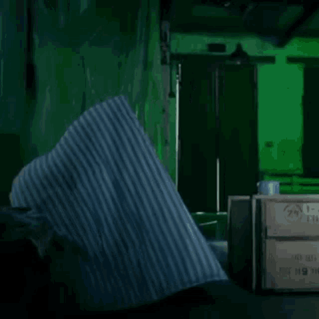 a person is laying on a bed in a dark room with a green background .