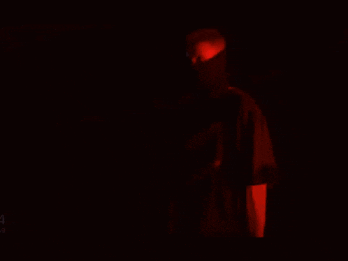 a man in a black hoodie is standing in front of a red and pink wall