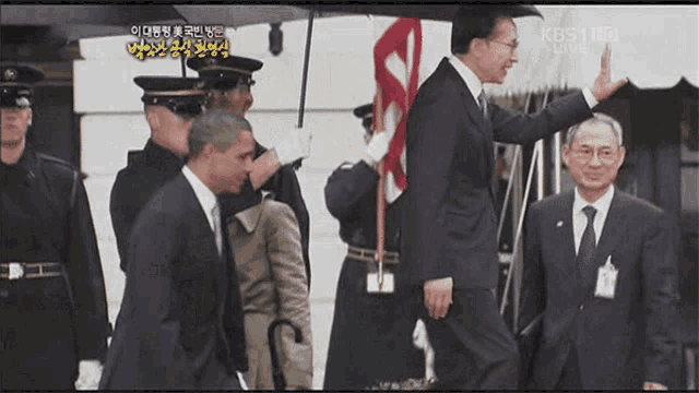 a man in a suit and tie is waving at another man in a suit