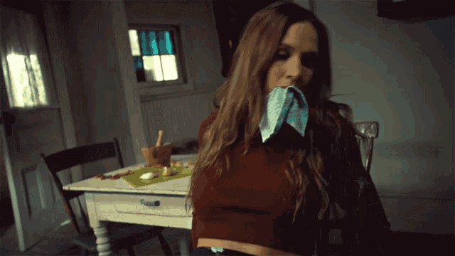 a woman wipes her mouth with a cloth in a kitchen