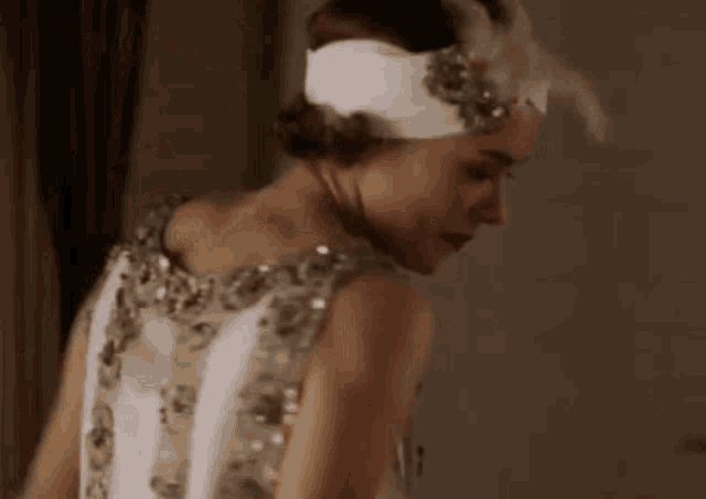 a woman wearing a white dress and a headband with feathers is standing in a room .