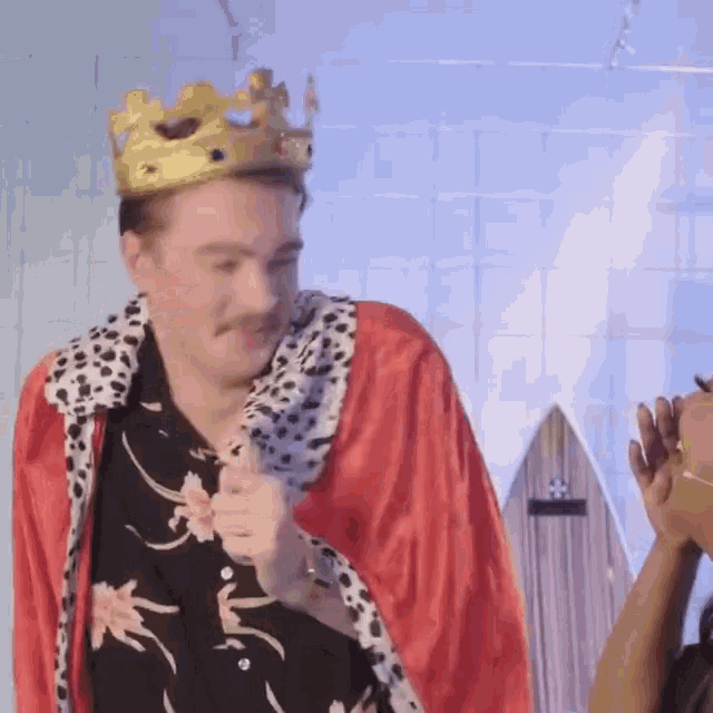 a man is wearing a crown and a red robe