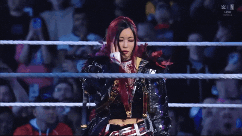 a woman with red hair is standing in a wrestling ring with the word win on the bottom