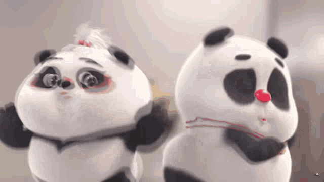 two panda bears are standing next to each other